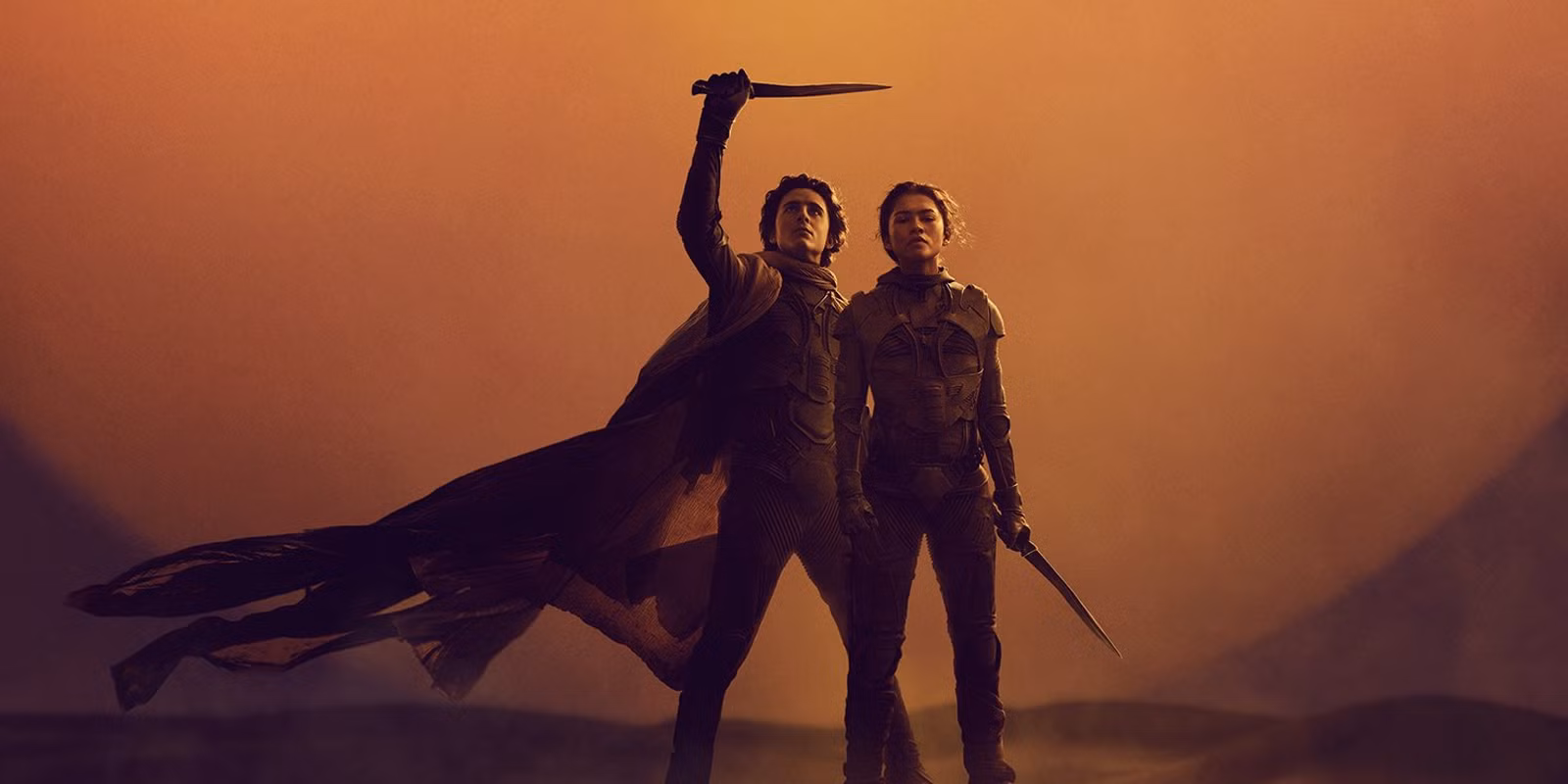 Paul Atreides och Chani stående på en sanddyné på Arrakis med en stor solnedgång i bakgrunden